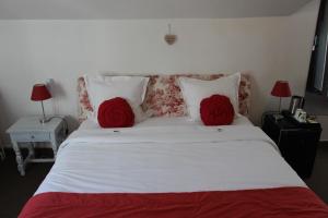 a bedroom with a white bed with two red pillows at Hôtel Beausoleil in Montélimar