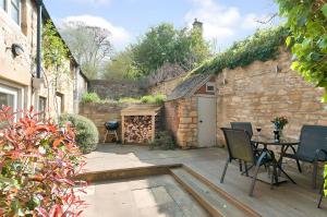 um pátio com uma mesa e cadeiras e um edifício em Cidermill Cottage em Chipping Campden