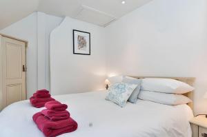 um quarto com toalhas vermelhas numa cama branca em Cidermill Cottage em Chipping Campden