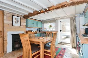 uma cozinha com uma mesa e cadeiras de madeira e uma lareira em Cidermill Cottage em Chipping Campden