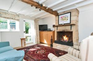 a living room with a fireplace and a tv at Cidermill Cottage in Chipping Campden