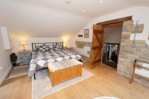 a bedroom with a bed and a stone wall at The Old Forge in Somerton