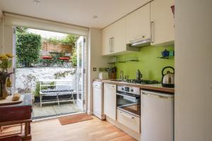 eine Küche mit weißen Geräten und einer offenen Tür zu einer Terrasse in der Unterkunft Whiteleaf Cottage in Lyme Regis