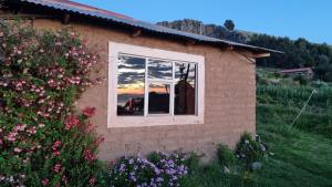 ein Haus mit dem Spiegelbild des Sonnenuntergangs in einem Fenster in der Unterkunft Inca lodge - Amantani in Ocosuyo