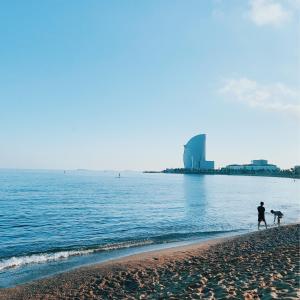 a man and his dog walking on the beach at TOC Hotel Las Ramblas in Barcelona