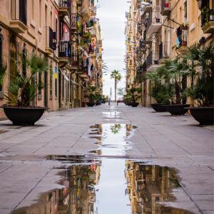 an empty street with a reflection of buildings in a puddle at TOC Hotel Las Ramblas in Barcelona