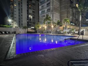 a large swimming pool with blue water at night at Isla Verde Puerto Rico, One Queen Bed in San Juan