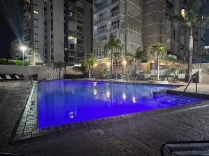 - une grande piscine d'eau bleue la nuit dans l'établissement Isla Verde Puerto Rico, One Queen Bed, à San Juan