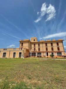 a large building with a grass field in front of it at Hotel La Lampara in Reggio Calabria