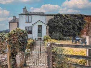 una casa vieja con una valla delante de ella en The Gilpin Farmhouse, Lake District Getaway, en Levens
