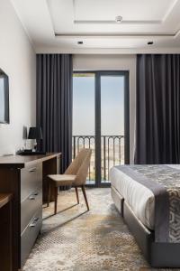 ein Hotelzimmer mit einem Bett, einem Schreibtisch und einem Fenster in der Unterkunft Shamsan Airport Hotel in Taschkent