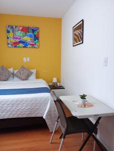 a bedroom with a bed and a desk and a table at Hotel Maceo 55 - Colonial Inn in Bogotá