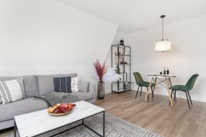 een woonkamer met een grijze bank en groene stoelen bij Design Apartment nah Messe & Rhein I Netflix I Küche in Krefeld