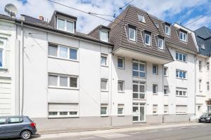 een wit appartementencomplex met een grijs dak bij Design Apartment nah Messe & Rhein I Netflix I Küche in Krefeld