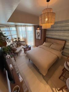 a bedroom with a large bed and a living room at Suelo at Azure North Pampanga in San Fernando