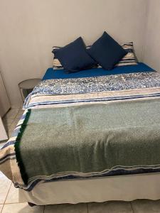 ein Bett mit blauen Kissen darüber in der Unterkunft Alvin's House in Tsumeb