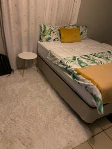 Un dormitorio con una cama con una mesa al lado. en Alvin's House, en Tsumeb