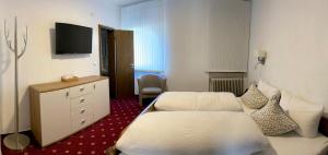 a hotel room with two beds and a television at Hotel Alessandro in Neuried