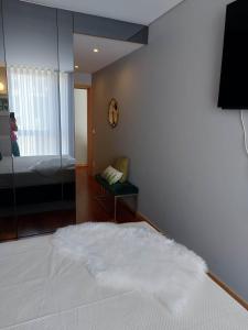 sypialnia z białym łóżkiem i lustrem w obiekcie Appartement en face de la mer w mieście Azurara