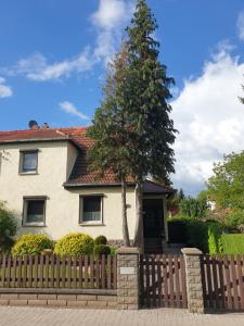 uma casa com uma cerca de madeira e uma árvore em Ferienhaus Hahn em Bad Frankenhausen