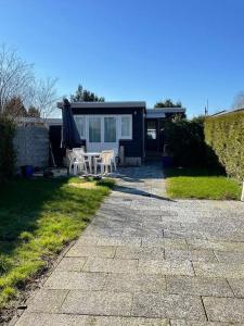 een patio met een tafel, een parasol en een huis bij Mooie chalet met grote tuin dichtbij Amsterdam in Opmeer