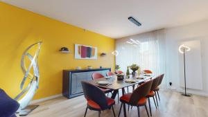 uma sala de jantar com mesa e cadeiras e uma parede amarela em Maison Mandarine Colmar 5 bedrooms 180m2 em Colmar
