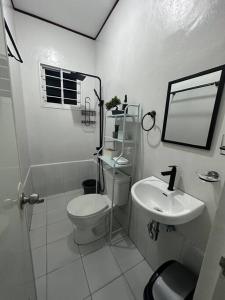 a white bathroom with a toilet and a sink at TymCast's Place - 2 Story house in Kabankalan