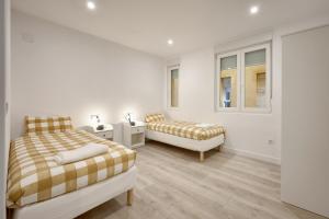 a white bedroom with two beds and two windows at Casita Mela - Apt. p/8 pax con terraza en Logroño in Logroño