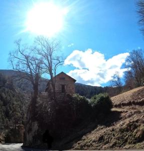 une maison sur une colline avec le soleil dans le ciel dans l'établissement Maison Maralpine, à Roubion