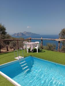 a swimming pool with a table and a table and chairs at Farm seaview on Capri in Termini