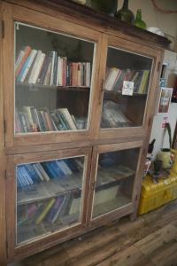 a wooden cabinet with glass doors filled with books at Dream Vision Guest House in Diu