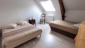 a bedroom with two beds and a chair in it at Gîte de La Basse Roche in Sougé