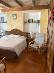 a bedroom with a bed and a chair at Camere e accoglienza LA CASA DELLA NONNA in Borzonasca