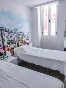two beds in a room with a mural on the wall at OLOPO in Porto