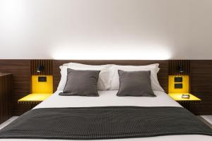 a bedroom with a large bed with two yellow lights at Spazio Gagarin Residence in Matera