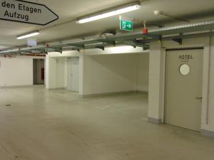 an empty parking garage with a green exit sign at Hotel Efcannos Dornberg Carree in Vechelde