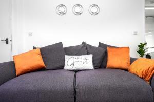 a couch with orange and black pillows on it at Springland Close in Ipswich