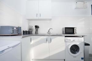 a white kitchen with a washing machine and a microwave at Springland Close in Ipswich