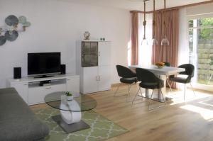 un soggiorno con tavolo, sedie e TV di Haus Buchenhof a Heringsdorf