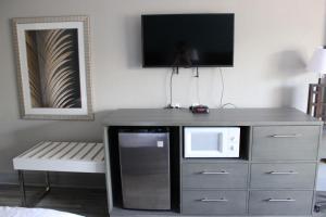 a room with a microwave and a tv on a dresser at Village Inn Destin in Destin