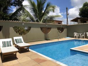 einen Pool mit zwei Stühlen und einer Palme in der Unterkunft Pousada Villas do Arraial in Arraial d'Ajuda