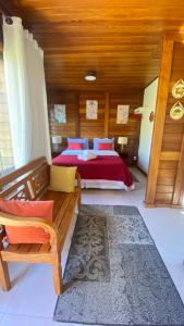 a bedroom with a bed with red sheets and a wooden ceiling at Pedacinho de Chão Chalés in Visconde De Maua
