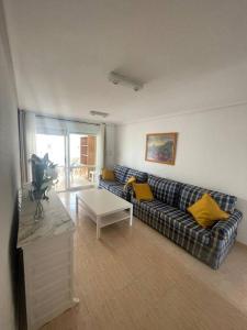 ein Wohnzimmer mit einem Sofa und einem Tisch in der Unterkunft Amplio y luminoso apartamento con piscina in Cala de Finestrat