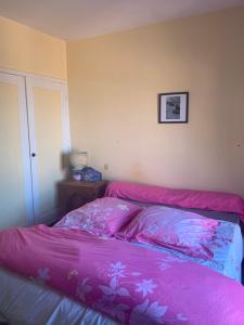 Una cama con una manta rosa encima. en Le Mas des Cabris, en Tourtour