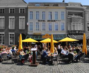 um grupo de pessoas sentadas em mesas em frente a um hotel em Stadshotel De Klok em Breda