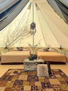 une tente avec 2 lits et une horloge dans une chambre dans l'établissement Utopia Feels Botanical Glampground and Micro-Farm, à Coldstream