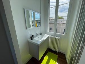 a white bathroom with a sink and a window at LA DOUCE Saumuroise in Angers