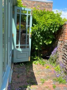 an open door to a garden with flowers at Pretty Cottage in Central Lewes in Lewes