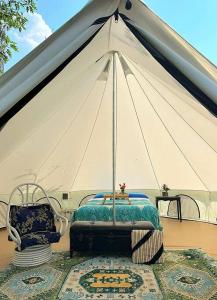 une tente avec un lit et deux chaises devant elle dans l'établissement Utopia Feels Botanical Glampground and Micro-Farm, à Coldstream