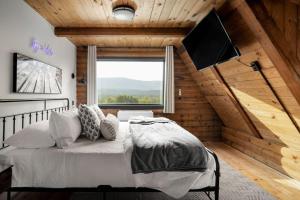 een slaapkamer met een bed en een flatscreen-tv bij Riverside Rose Cabin: Luxe*LogCabin*MtnView*Sleeps12*Secluded*Shenandoah in Rileyville